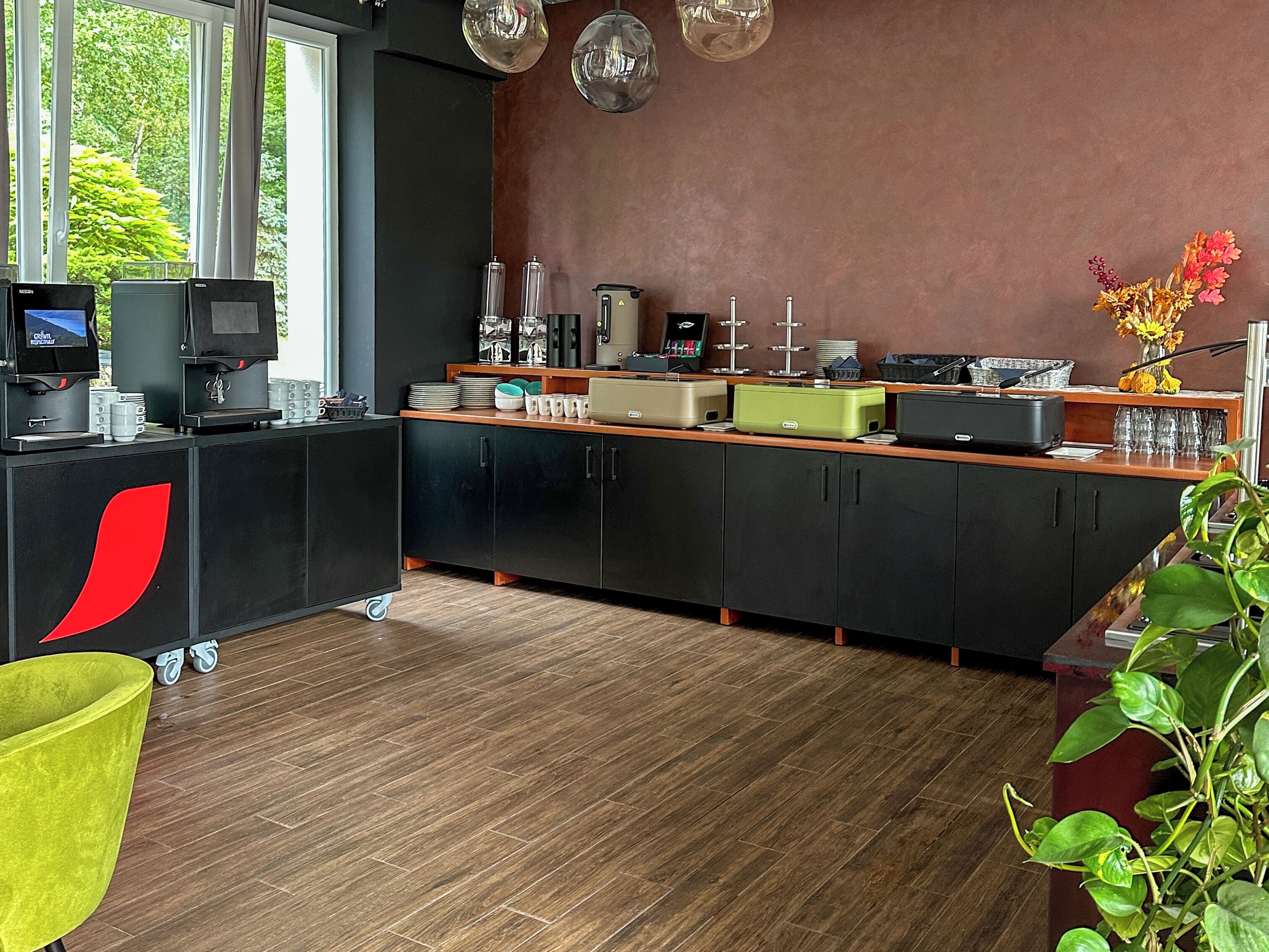Une cuisine moderne dotée d’un coin café, d’une grande fenêtre et offrant une vue sur la verdure environnante.