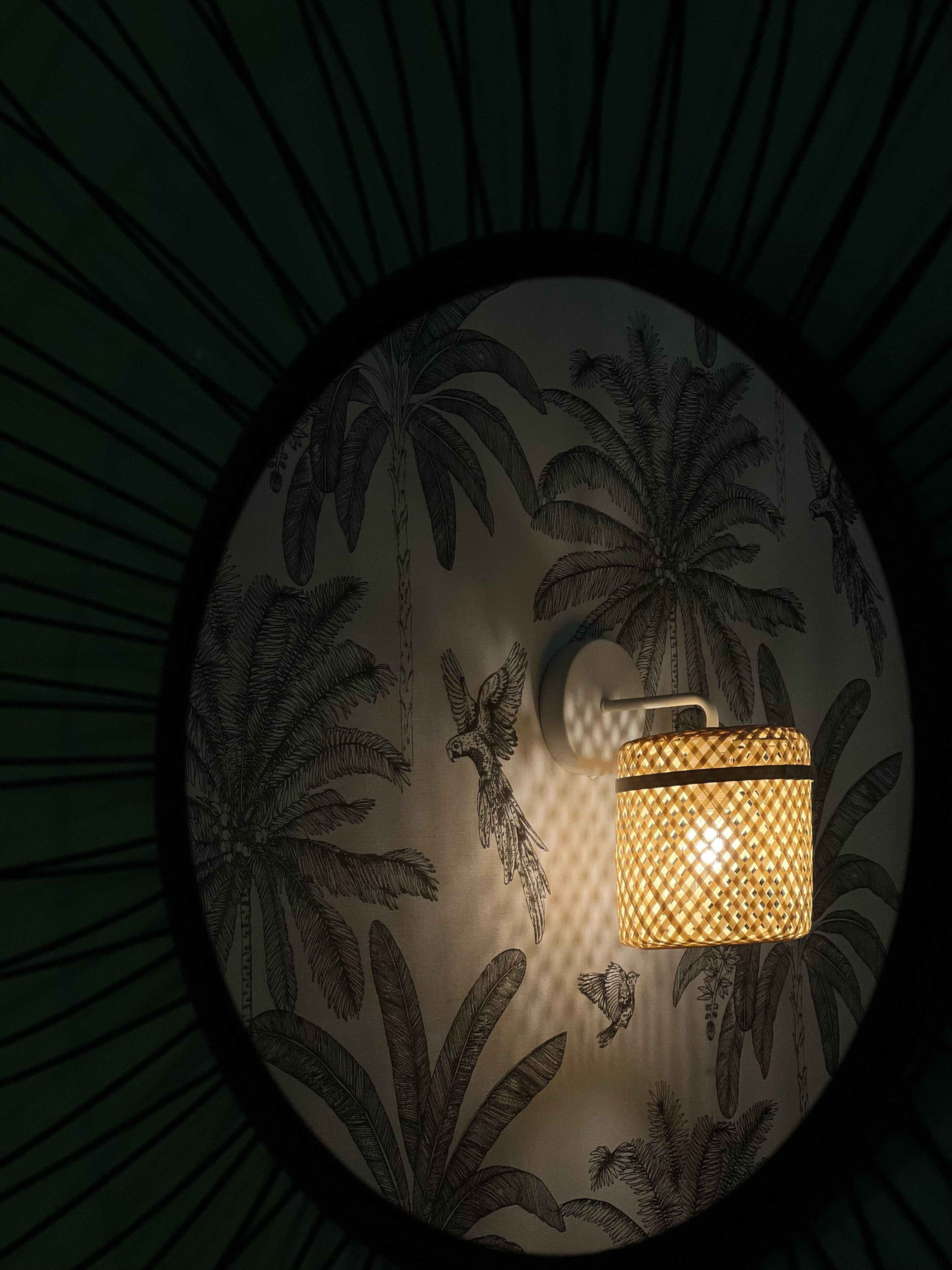 A circular wall with a central light fixture and a tropical leaf pattern.