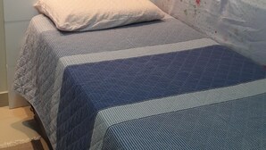 Quarto com cama, mesa de cabeceira, penteadeira e janela.
