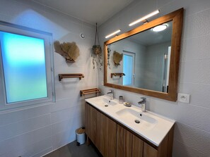 Ein modernes Badezimmer mit einem großen Spiegel, zwei Waschbecken und Holzschränken.