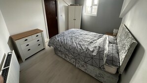 A bedroom with a bed, a wardrobe, a dresser, and a window.