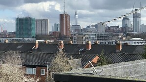 A cityscape with multiple buildings, including a prominent red tower and a green building under construction.