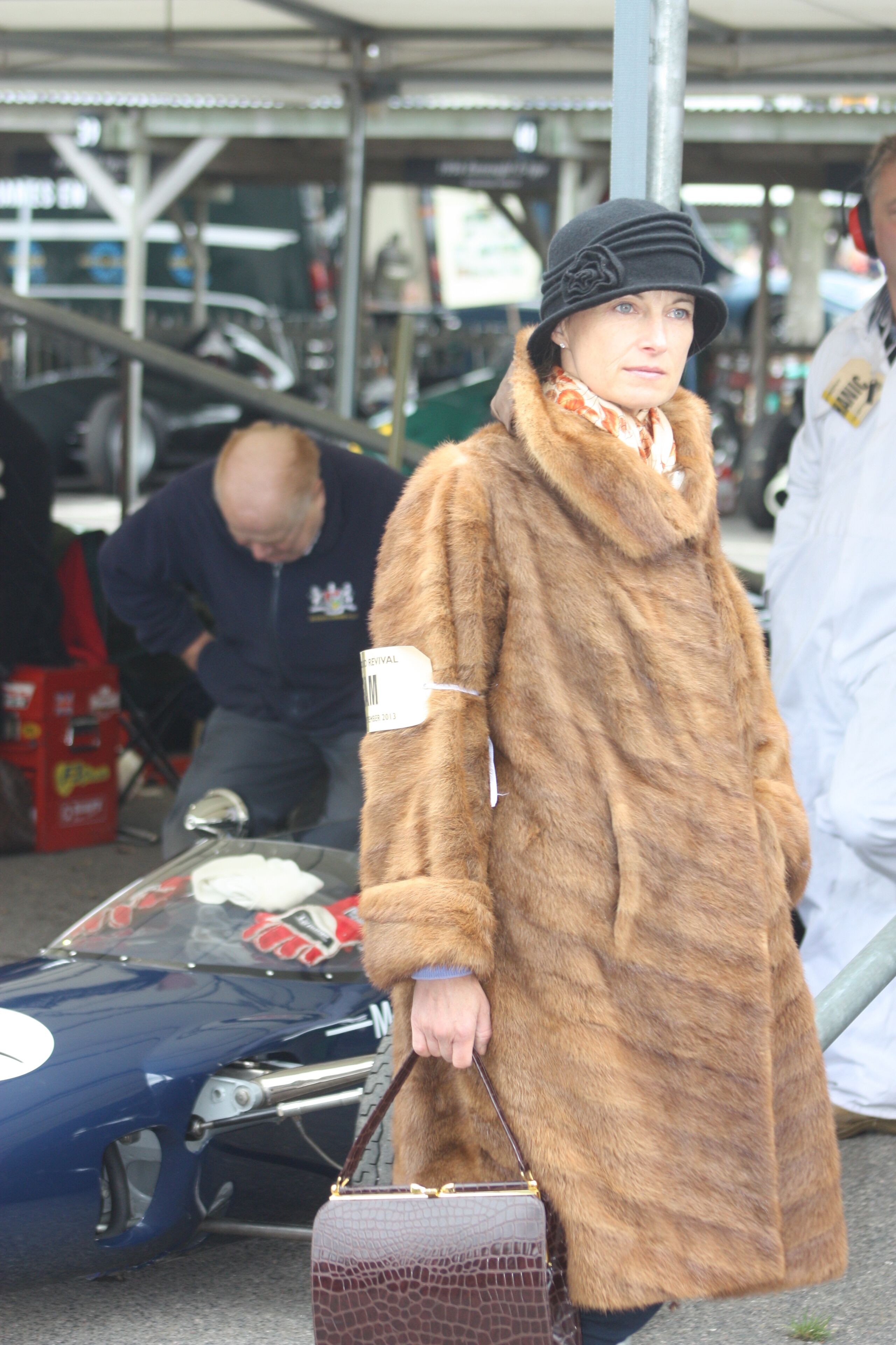 A person in a long fur coat holding a handbag.