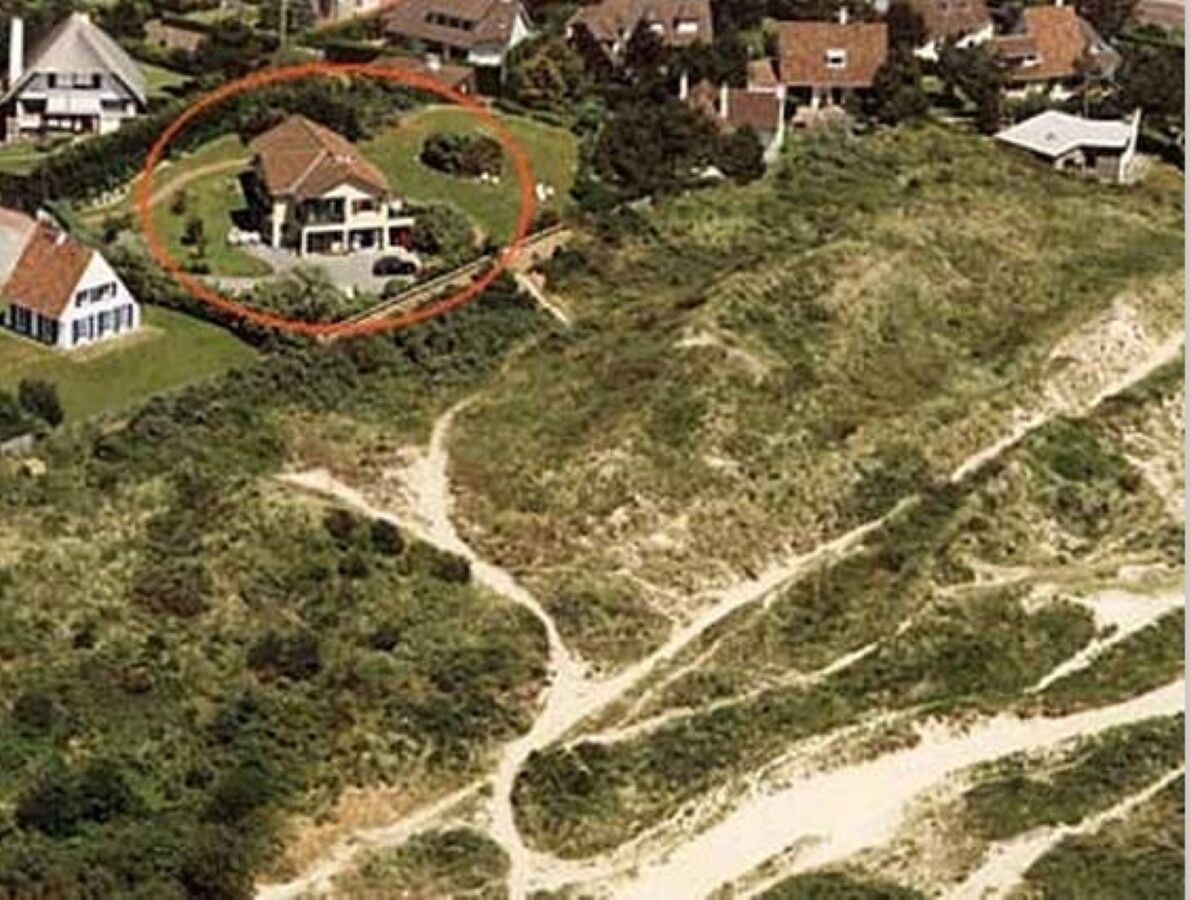 Vue aérienne d’un quartier résidentiel avec des maisons, un chemin de terre sinueux et une propriété encerclée.