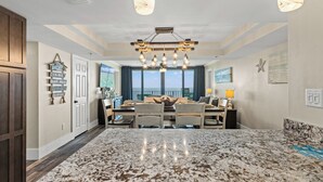 A spacious kitchen with a large island, modern pendant lights, and a view of the ocean. - Watercrest 1704 - Serenity Shores (Panama City Beach)