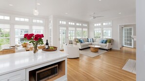 Un salon spacieux avec un canapé blanc, une table basse et un coin repas comprenant une table et des chaises blanches.