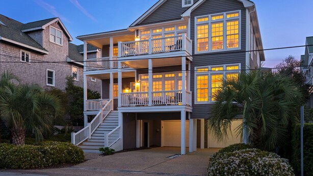 Une maison à deux étages avec un balcon à l’étage supérieur, un porche à l’avant et un escalier menant à l’entrée.
