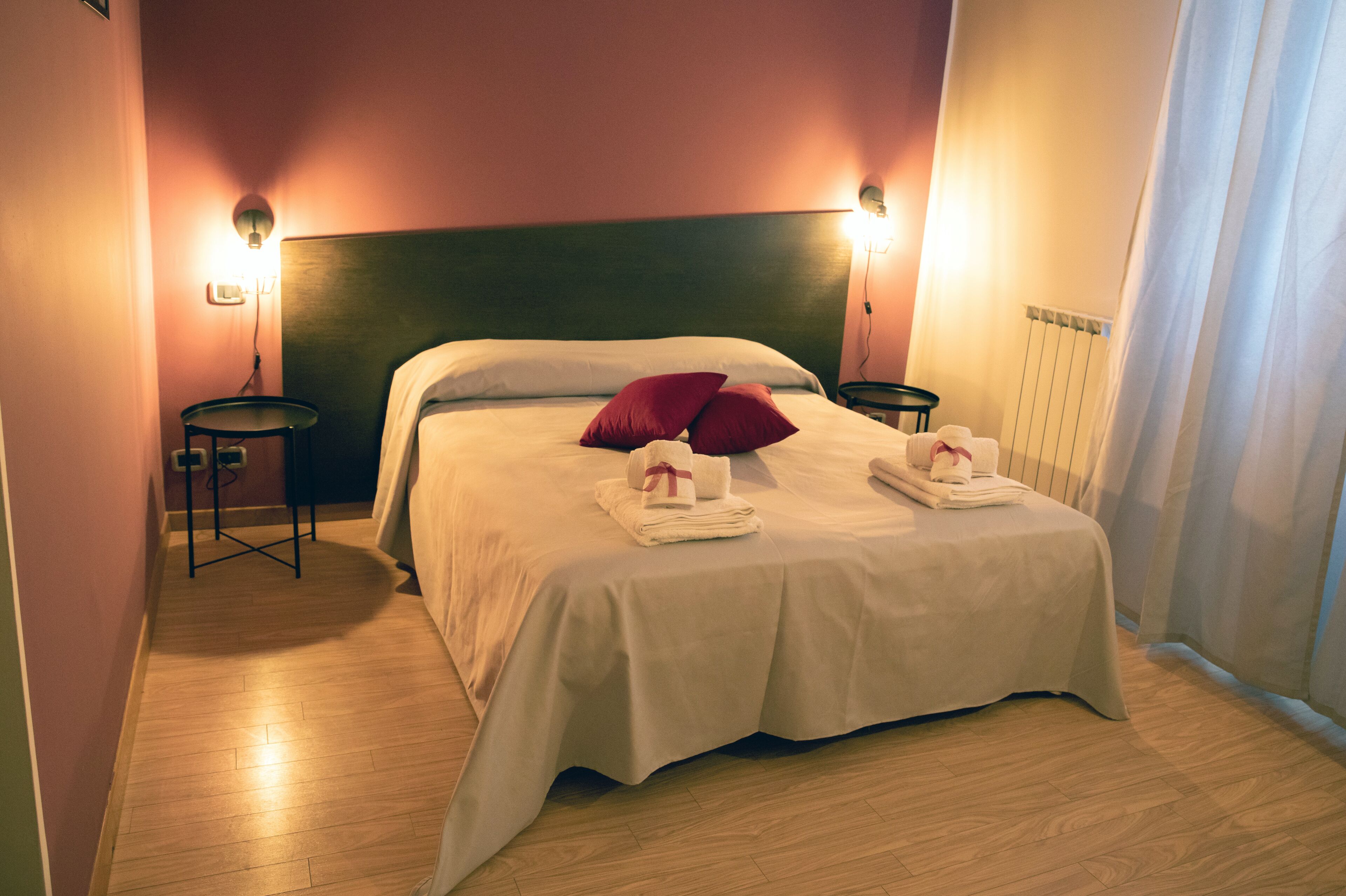 Una cama bien hecha con almohadas, una mesita de noche y una lámpara de pared.