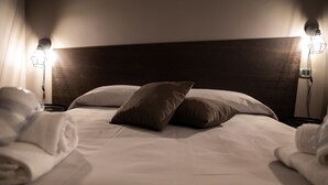 Una cama bien hecha con dos almohadas y dos lámparas de noche.