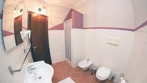 Un baño con lavamanos, bidé, inodoro y espejo.