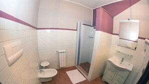 Un baño con paredes de azulejos blancos, ducha, lavamanos e inodoro.