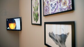 Una pared con tres cuadros enmarcados y una pantalla de televisión que muestra un paisaje de atardecer.