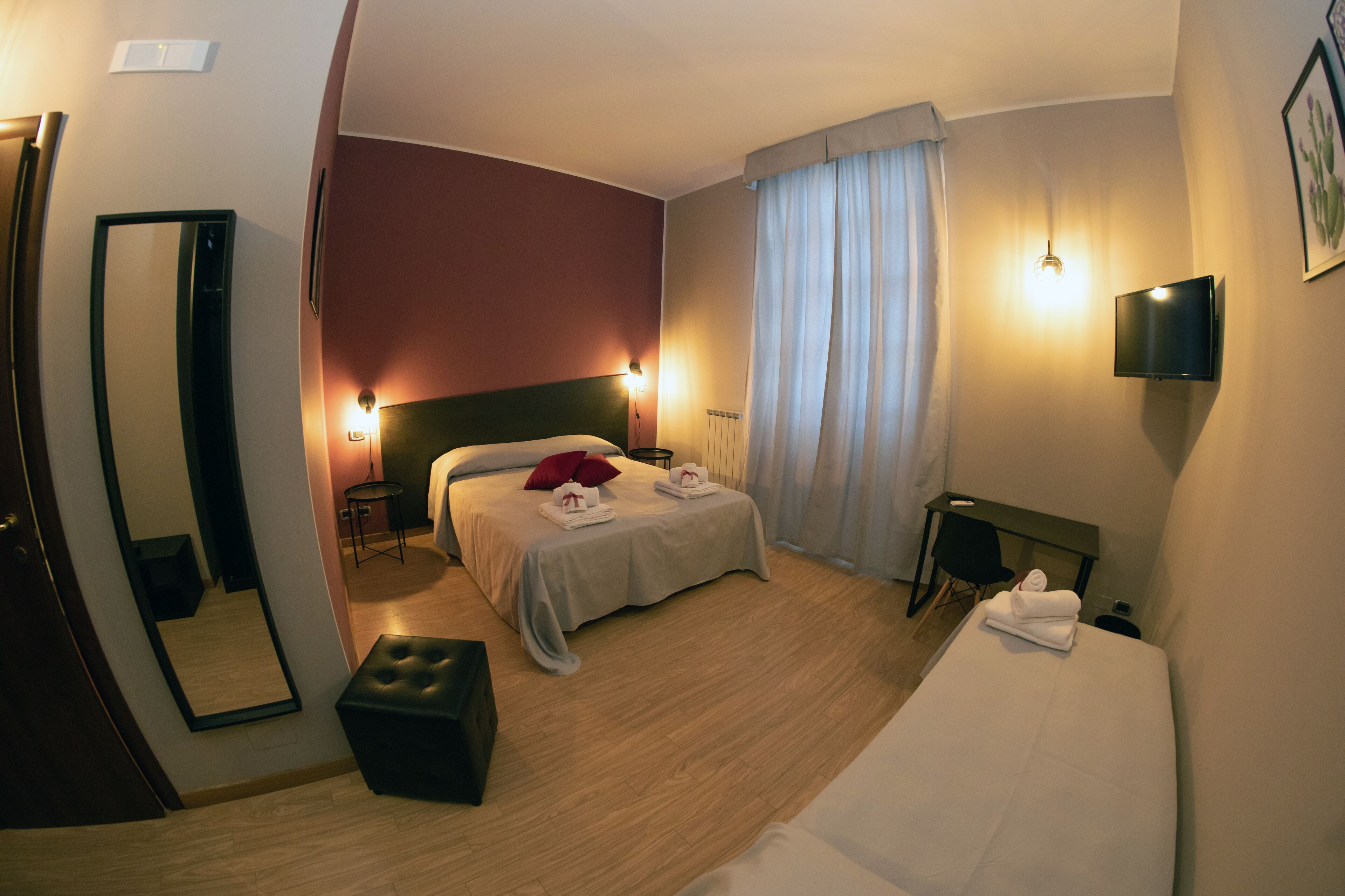 Une chambre d’hôtel équipée d’un lit, d’un bureau, d’une chaise, d’un miroir et d’une télévision.