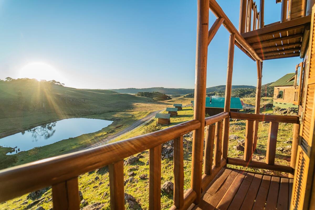 Een houten terras met uitzicht op een meer en heuvels.