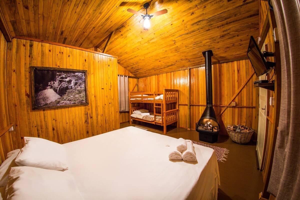 Een houten kamer met stapelbedden, een open haard en een ingelijst schilderij aan de muur.