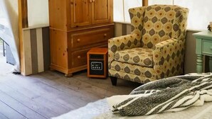 A room with a wooden cabinet, patterned armchair, and a bed with a patterned bedspread. - Glamping Tent! Nestled at base of Mission Mountains! Quiet & secluded.  (Ronan)