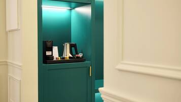 A teal-colored elevator with a coffee machine and a small table.