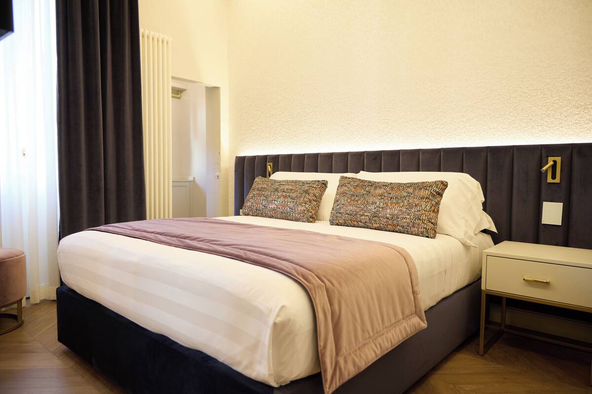 A neatly made bed with a headboard, a bedside table, and a chair.
