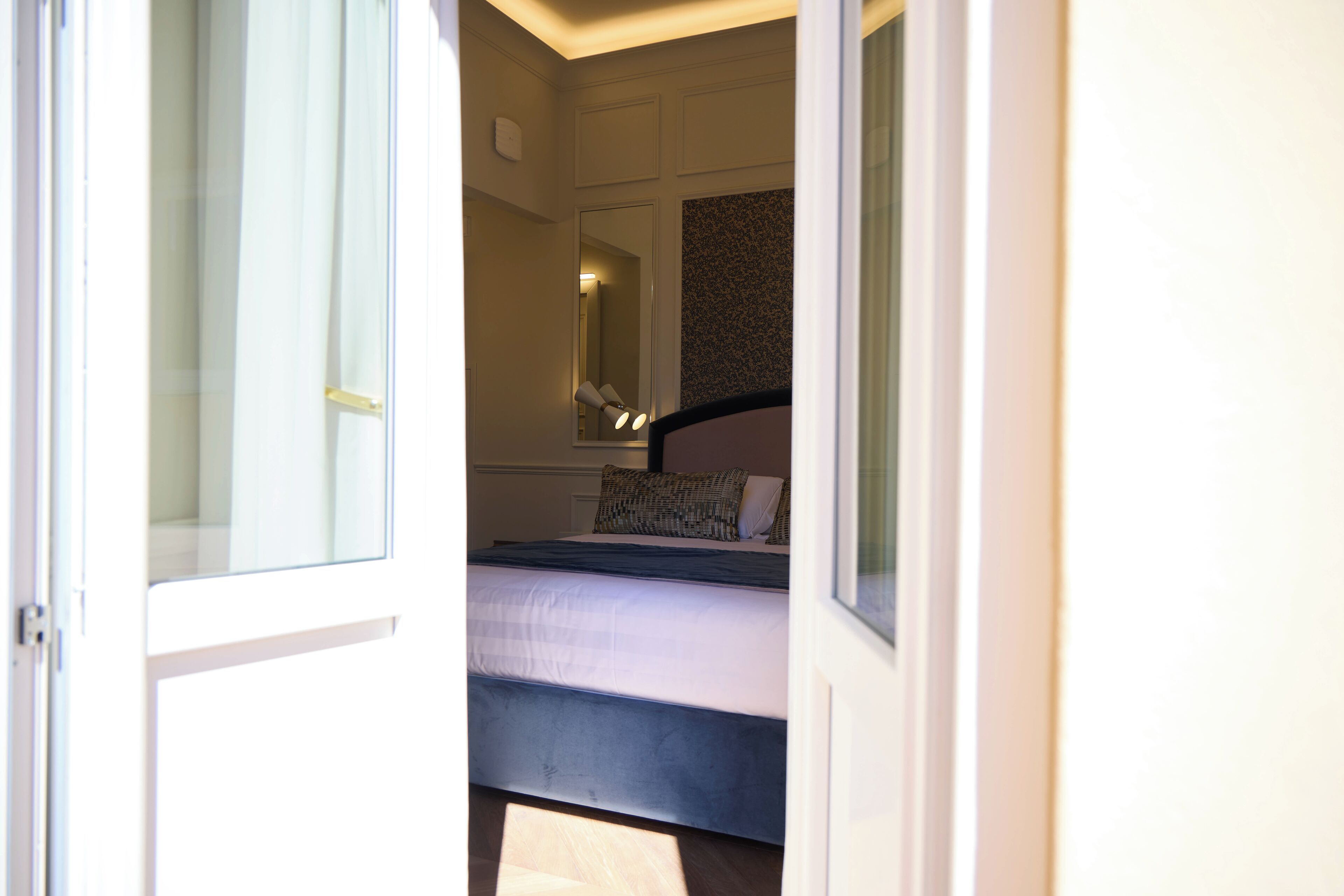 A bedroom with a bed, a mirror, and a window.