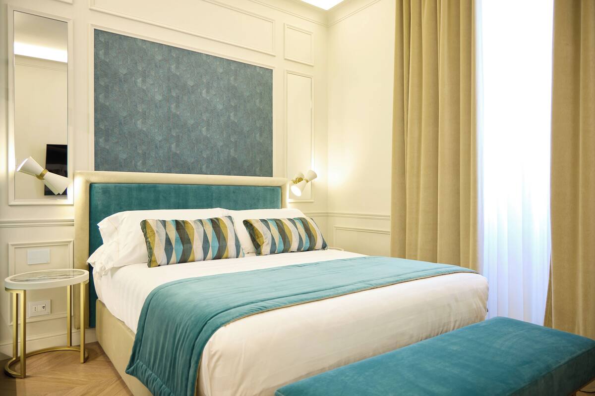 A neatly arranged bedroom with a large bed, a bedside table, and a wall-mounted artwork.