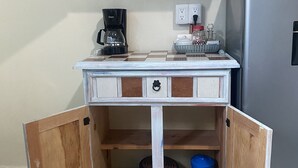 A compact kitchenette with a coffee maker, a small refrigerator, and a cabinet with dishes. - "Suite Serenity"- NEW Studio in PRIME location.10-minute walk to everything PV! (Puerto Vallarta)