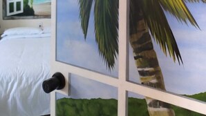 A bedroom with a bed, a window, and a wall with a tropical mural. - "Suite Serenity"- NEW Studio in PRIME location.10-minute walk to everything PV! (Puerto Vallarta)