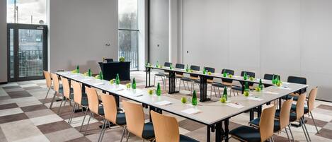 Un salón de conferencias con una larga mesa, sillas y un atril.