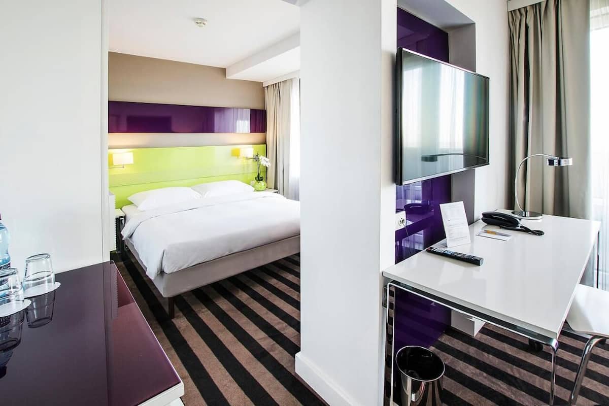 Une chambre d’hôtel comprenant un lit, un bureau avec un ordinateur, une télévision et une salle de bain.