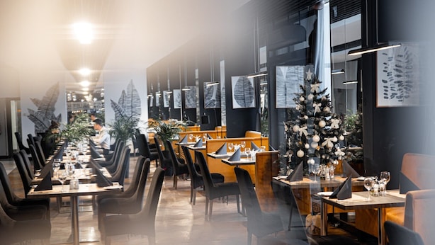 Un restaurant avec de longues tables, des chaises et un sapin de Noël.