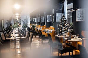 Un restaurante con mesas largas, sillas y un árbol de Navidad.