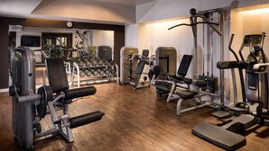Une salle de sport équipée de divers appareils d’exercice, d’une série de haltères et dotée d’un plancher en bois.