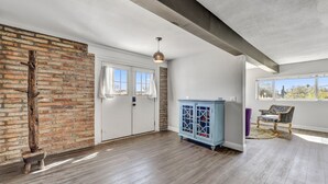Une pièce spacieuse avec un mur en briques, une porte blanche et une grande fenêtre.