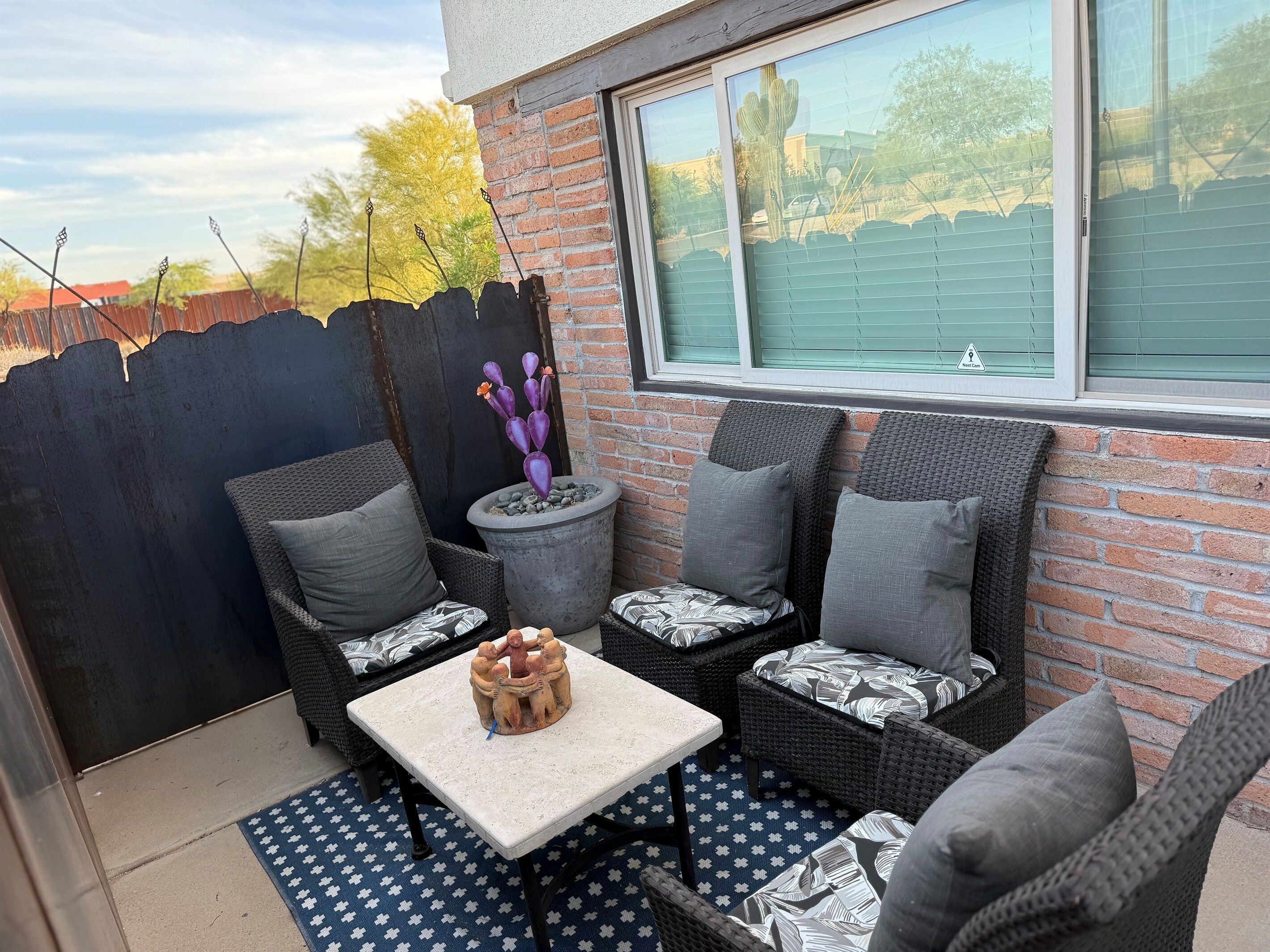 Eine Terrasse mit Korbmöbeln, einem Tisch und einem Blumentopf.