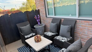 Une terrasse avec des meubles en osier, une table et une plante en pot.