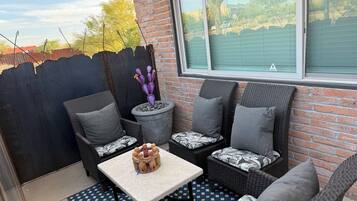 Eine Terrasse mit Korbmöbeln, einem Tisch und einem Blumentopf.