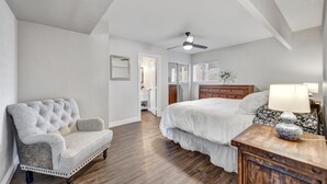 Une chambre à coucher comprenant un lit, une table de chevet, une chaise et un ventilateur de plafond.
