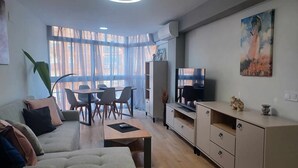 Un salon moderne comprenant un canapé, une table basse, un téléviseur et un coin repas.