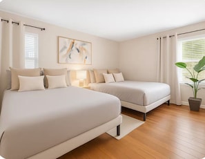 Un dormitorio con dos camas, una mesita de noche, una lámpara, un cuadro en la pared y una planta en maceta.