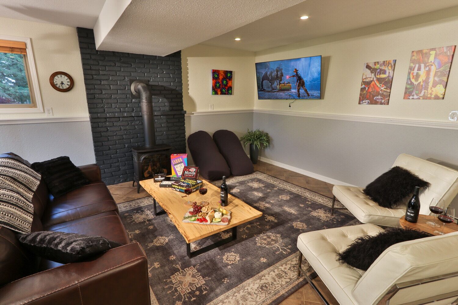 A cozy living room with a fireplace, comfortable seating, a coffee table with snacks, and artwork on the walls.