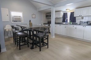 A modern kitchen with white cabinets, a central island with bar stools, a microwave, and a toaster.
