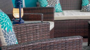 Mobilier en osier, avec un coussin et une lanterne.