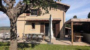 A two-story house with a patio, outdoor seating, and a pergola.