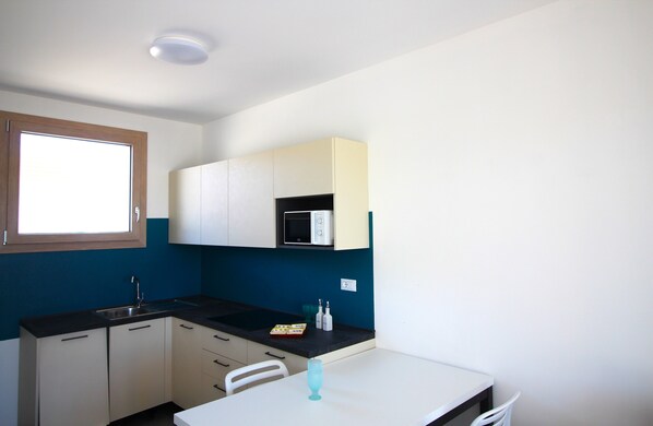 A compact kitchen with a window, a microwave, and a sink.