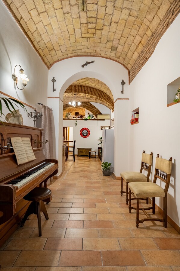 A cozy room with a piano, chairs, a dining table, and a brick ceiling. - Domus Gelsomino, Rome, Vatican, St. Peter's Square (Roma)