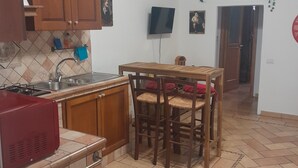 Eine Küche mit Holzausbau, einer Fliesenrückwand, einem roten Gerät und einem Essbereich mit einem Holztisch und Stühlen.