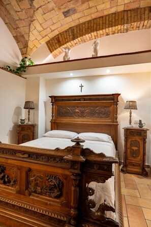 A bedroom with a wooden bed, a brick ceiling, and a cross on the wall.
