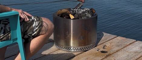 A wooden deck with a metal fire pit and a dog.