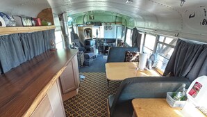 Un intérieur de camping-car compact comprenant un coin cuisine, un espace salon et un sol à motifs.