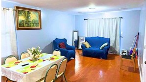 A dining area with a table set for four, a blue sofa, and a painting on the wall. - Glamour Room C 6mins to Newark Liberty (Newark)