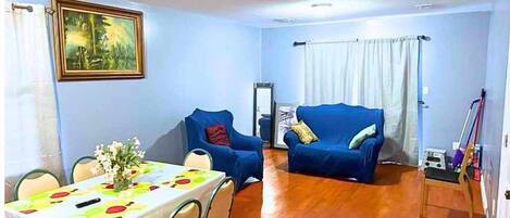 A dining area with a table set for four, a blue sofa, and a painting on the wall.